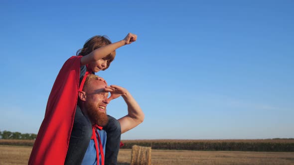 Dad Walking with Son on His Shoulders Across Field