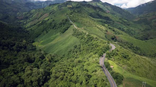 Aerial view flying above lush green tropical rain forest mountain with rain cloud cover during the r