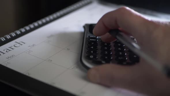 Hand with pen using calculator in January close up panning shot