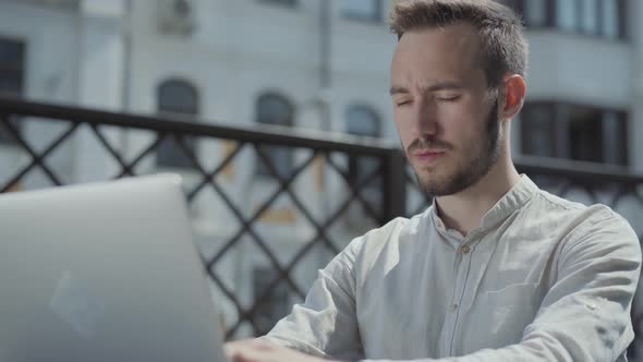 Portrait Bearded Young Man Sitting at the Table on the Terrace in Front of Laptop, Working