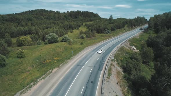 Aerial View of an Intercity Highway with Traffic Going Through a Green Forest on Bright Sunny Day