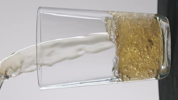 Vertical wide shot of beer getting poured into a glass. Studio shot with white background. Commercia