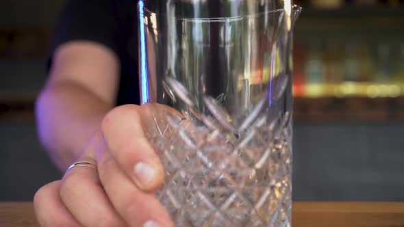 A Bartender Putting an Empty Glass with Patterns on Wooden Bar Table