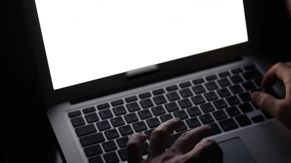 IT student studying hard at late night in dark room with laptop screen close-up. Developer