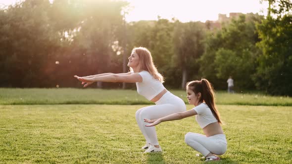 Young Woman and Her Kid Are Doing Morning Exercises Outdoors