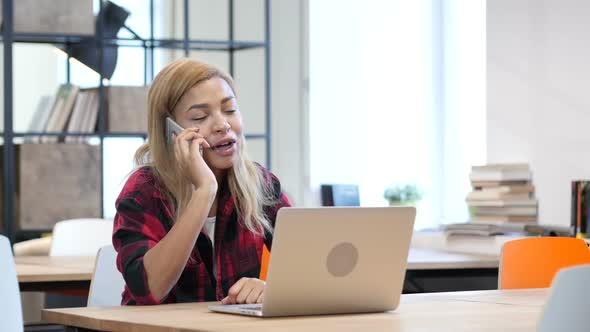 Black Woman Talking On Smartphone, Sitting in Office