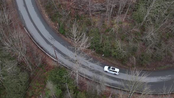 Suv car driving on rural road through forest. Aerial tracking