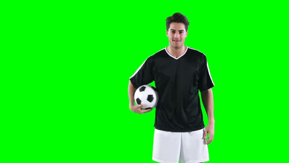 Football player holding a football against green screen