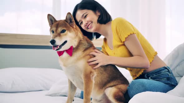 Young woman having fun playing with her dog in bedroom