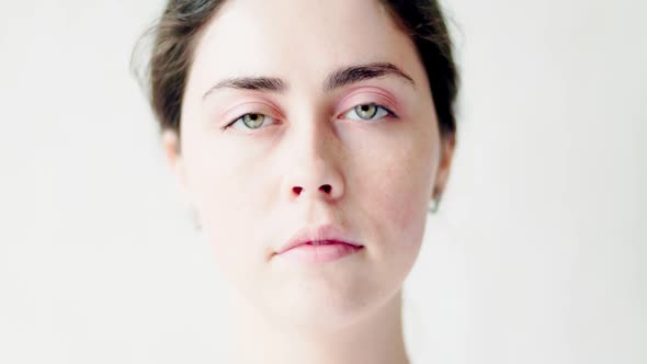 Close-up portrait of a young Caucasian sad woman on a white background