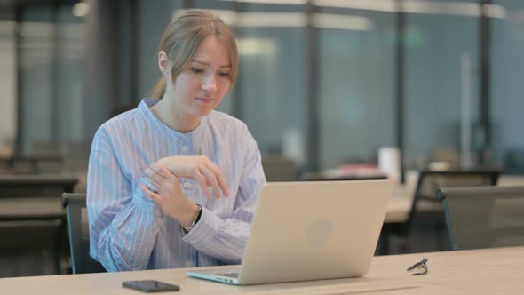 Young Woman Having Wrist Pain While Using Laptop in Office