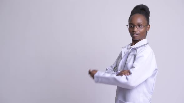 Profile View of Young Happy African Woman Doctor with Arms Crossed