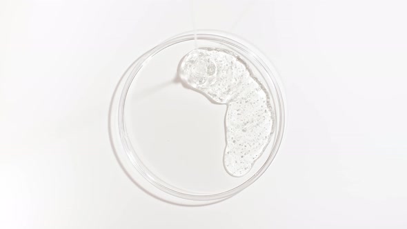 Transparent Cosmetic Gel Fluid Dripping Into the Glass Bowl of Petri alt