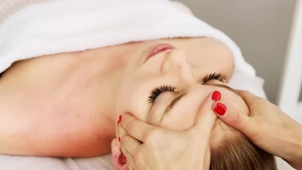 Beautician cosmetologist makes lifting face massage, professional cosmetic procedure