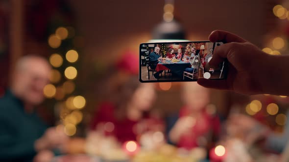 Festive Family Members Getting Photographed with Smartphone While Sitting at Table Enjoying