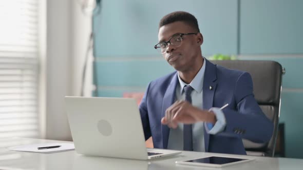 Young African Businessman Showing Thumbs Down Sign While Using Laptop in Office