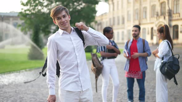 Portrait of Positive Confident Young Caucasian Man Hanging Backpack on Shoulder Smiling Looking at