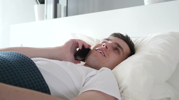 Man Talking on Phone while lying in Bed