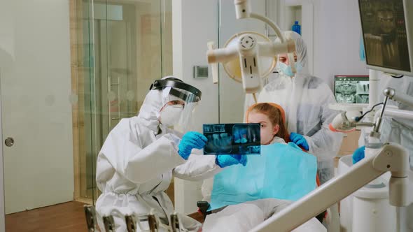 Doctor in Protective Suit Discussing About Xray of Tooth with Mother of Child