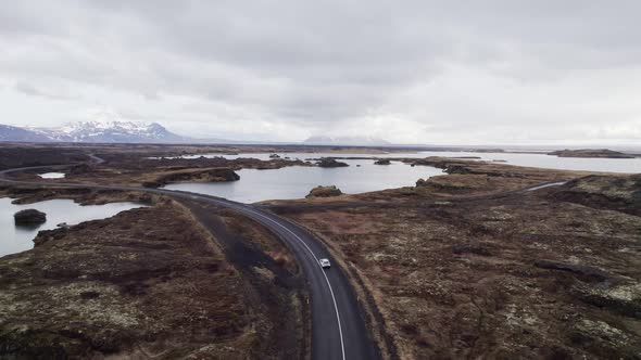 Aerial tracking view of a car driving near Lake Myvatn on gorgeous landscape in Iceland