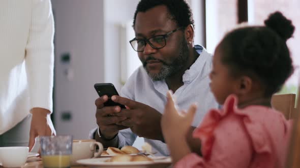 Smiling man looking at the phone after breakfast