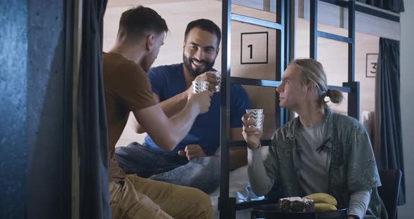 Three Positive Multiethnic Friends Celebrating Holiday in Hostel or Inn. Portrait of Happy Relaxed