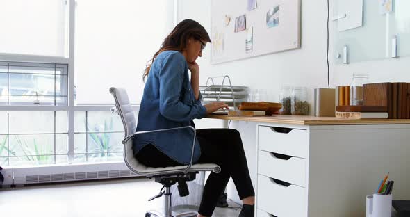 Female executive sitting at desk and using digital tablet