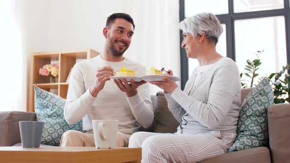 Senior Mother and Adult Son Eating Cake at Home