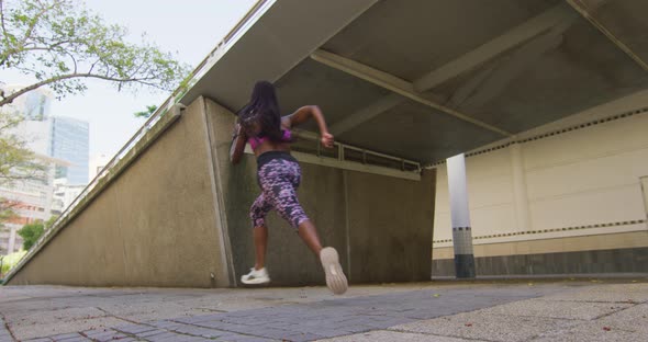 African american woman exercising outdoors running under bridge in the city