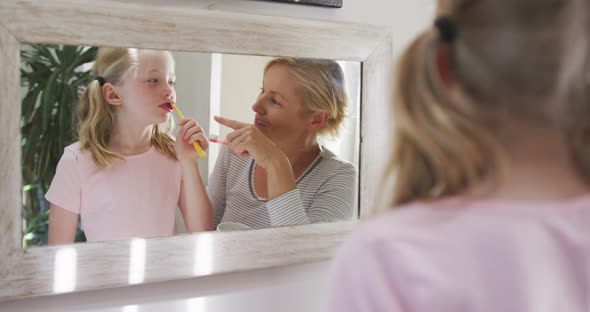 Over the shoulder view of Caucasian woman and her daughter brushing their teeth