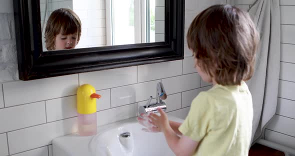 Little Boy in a Bathroom Washes with Hand Soap