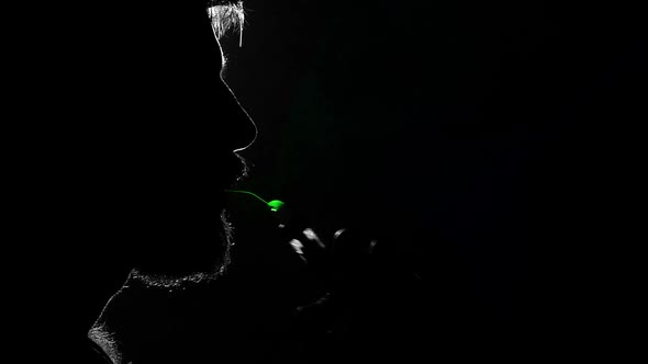 Man Smoking Electronic Cigarette. Multi-colored Smoke. Silhouette. Slow Motion