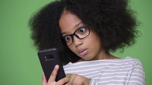 Young Cute African Girl with Afro Hair Looking Shocked While Using Phone