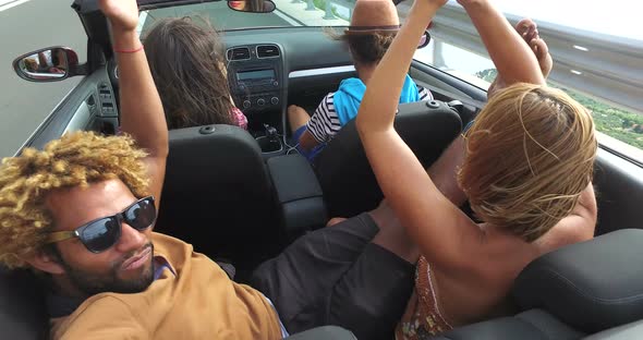 Handsome black man sticking his feet up of the convertible riding with friends