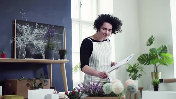 Florist checking delivery order while packing box with flowers