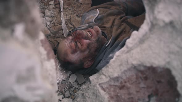 Aged Man Lying Under Remains of Destroyed Building