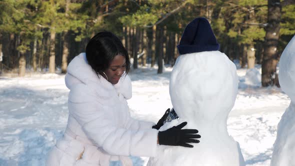 AfricanAmerican Girl Makes Snowman Among Winter Nature