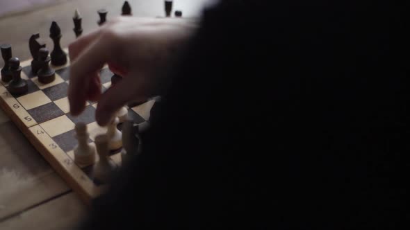 Closeup View From Back of Unrecognizable Chess Player Performing Move with Pawn Piece on Wooden