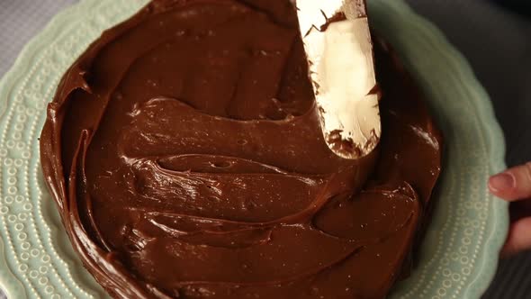 Icing a cake with chocolate frosting - top down close view