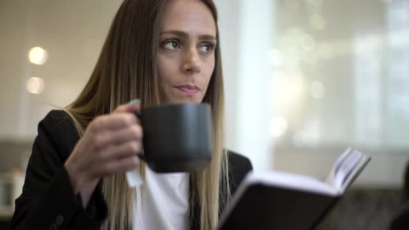 Businesswoman drinking coffee and reading diary