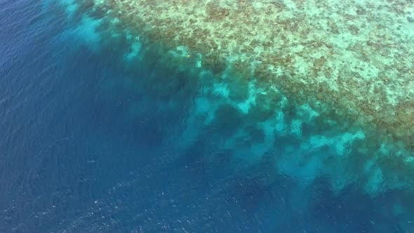 Aerial view of transparent water with coral near Maldives island.