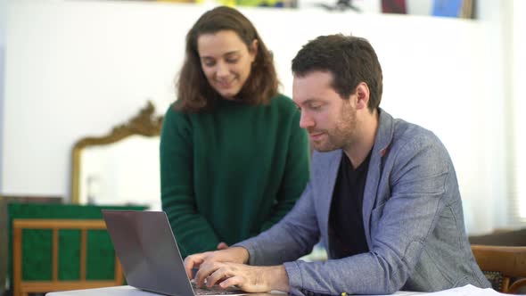 Man talking with colleague while working in laptop computer