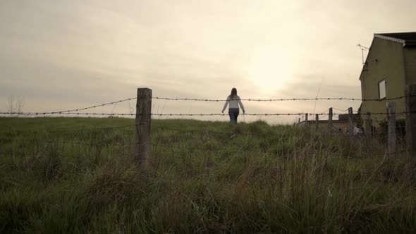 Woman walking through barbed wire field