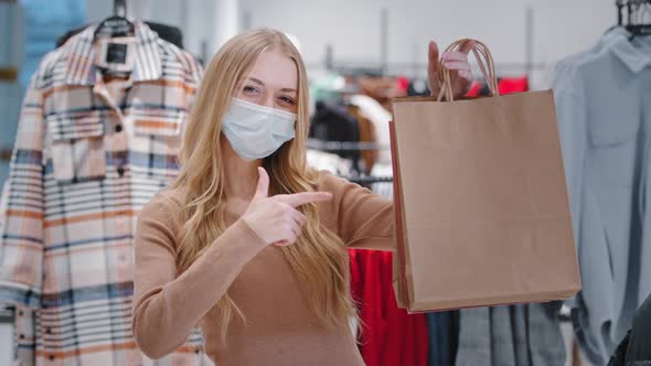 Closeup Happy Young Woman in Medical Mask During Pandemic Stand in Clothing Store Approval Gesture