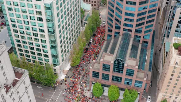 A Massive Crowd of People March in the City Street, Top Down Drone Reveal