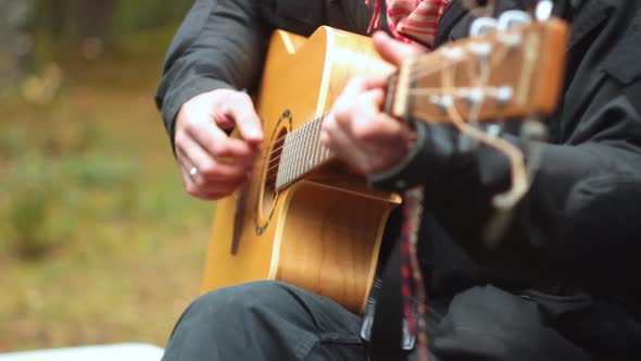 man in black clothes playing acoustic guitar outdoors