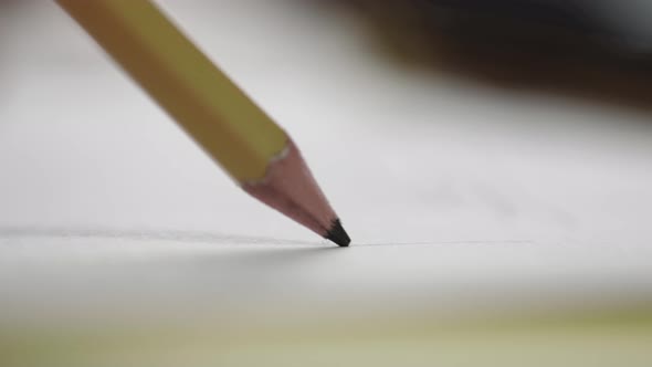 A close-up of a slate pencil draws on a white sheet of paper. Drawing or sketching.