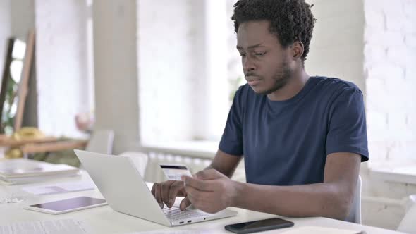 Young African Man Using Credit Card on Laptop