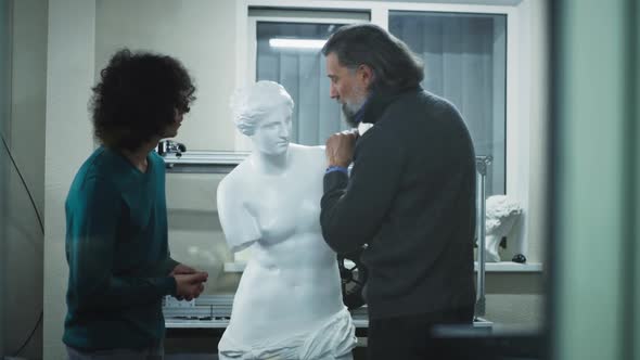 Male Designers Examining Face of Plastic Statue