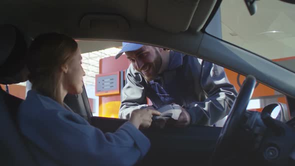 Gas Station Attendant Collecting Payment Through Car Window